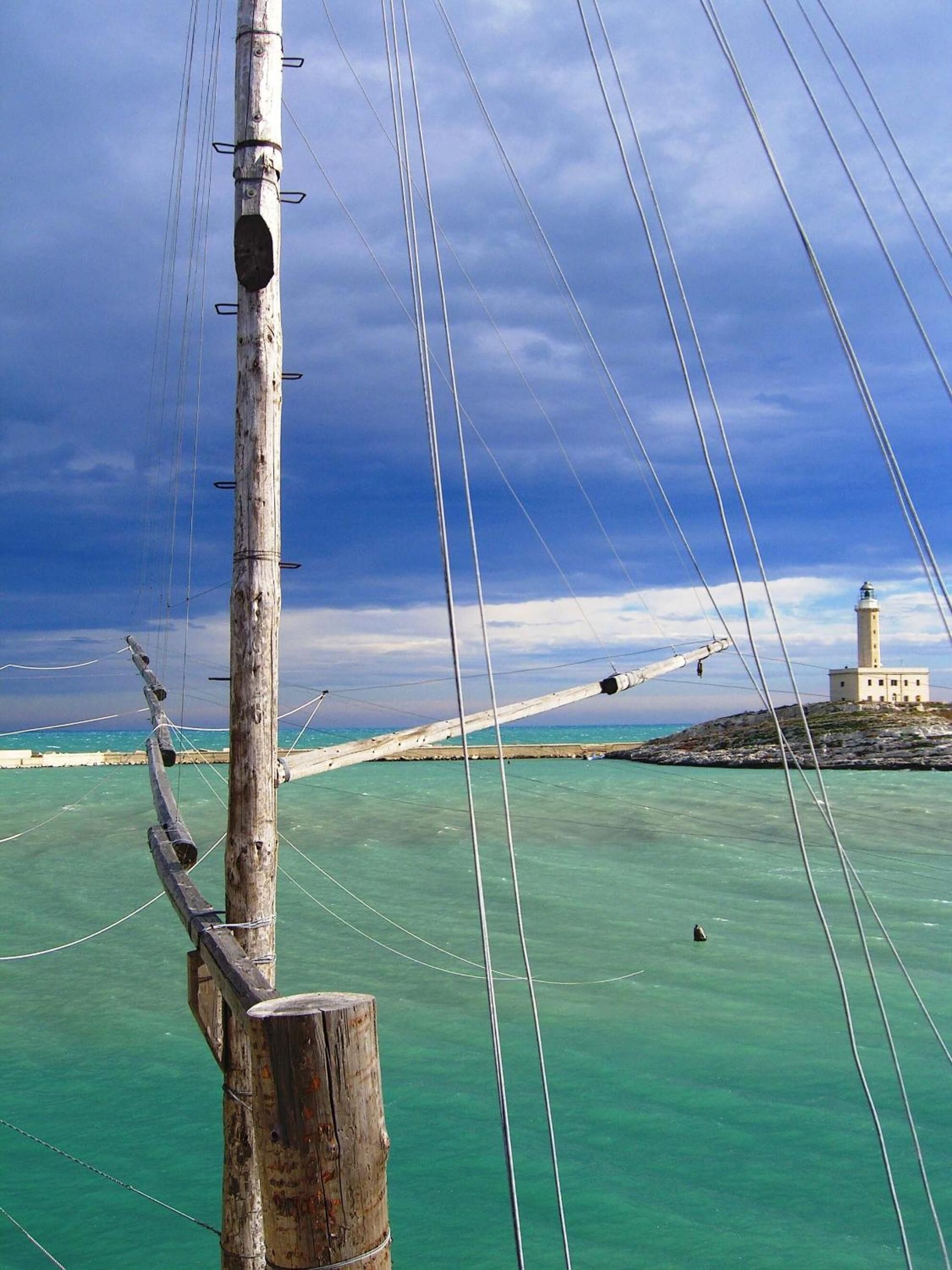 A lighthouse on a rocky outcrop with clear turquoise waters.