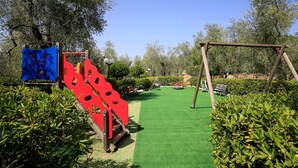 A playground with a red slide and a swing set. - Residence Valleverde (Vieste)