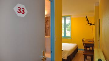 Een kamer met een bed, een bureau en een raam.