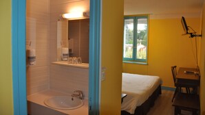 Un baño con lavamanos, espejo y ventana.