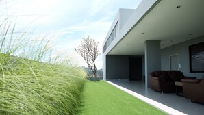Ein modernes Gebäude mit flachem Dach, einer Grünfläche und einer Sitzecke mit zwei Sofas.