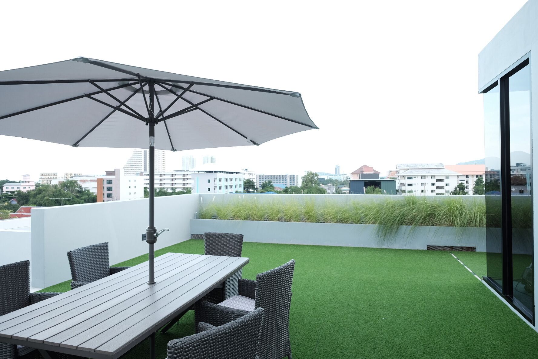 Una terraza en la azotea con una mesa, sillas, una sombrilla y vistas de la ciudad.