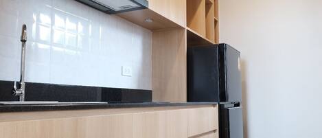 Una cocina moderna con armarios de madera, un refrigerador negro y un microondas.