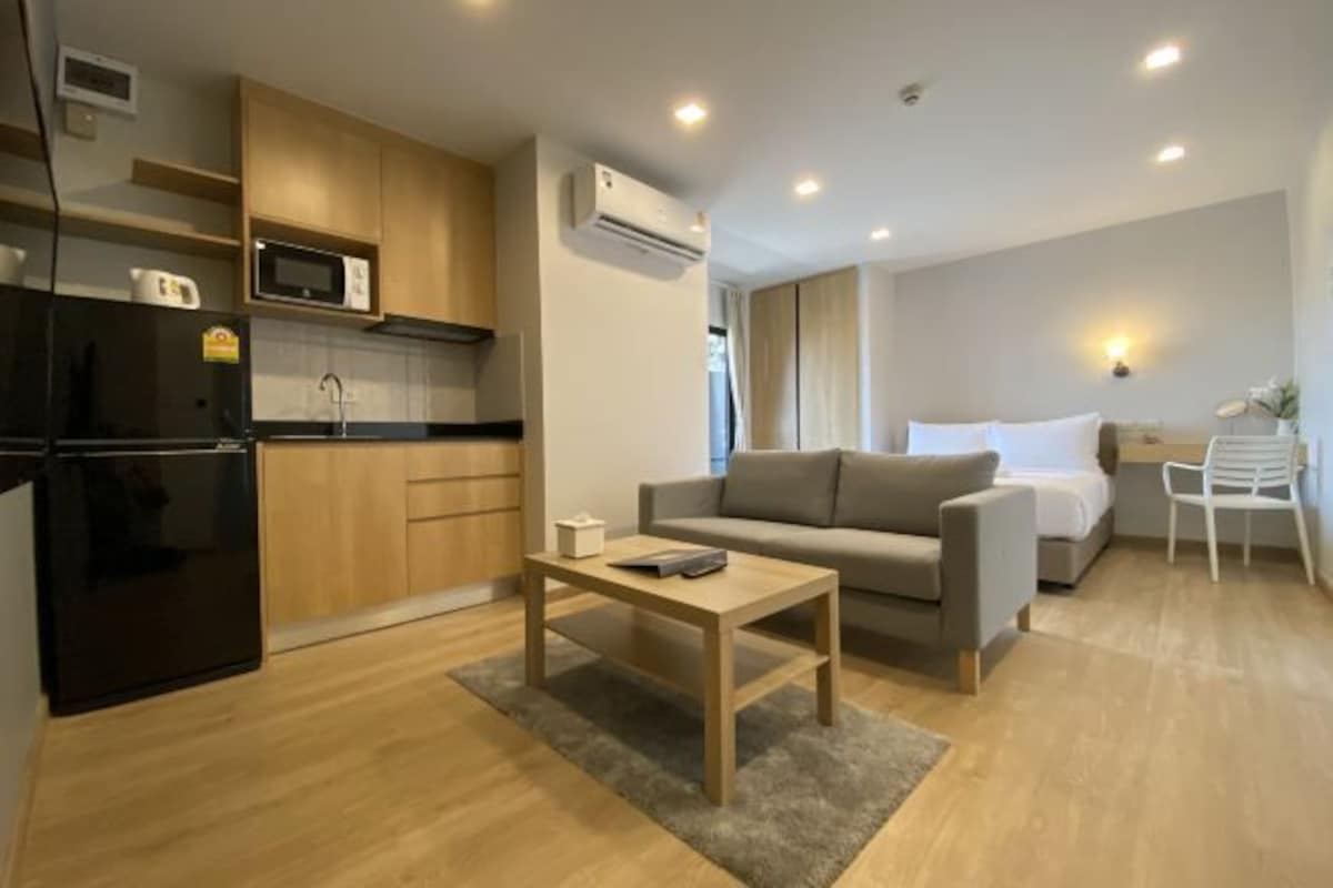 Un espacio habitable compacto con kitchenette, sofá, cama y una mesita.