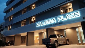 Ein mehrstöckiges Gebäude mit einem Schild, auf dem „MALEESA PLACE“ steht, das Serviced Apartments anzeigt.