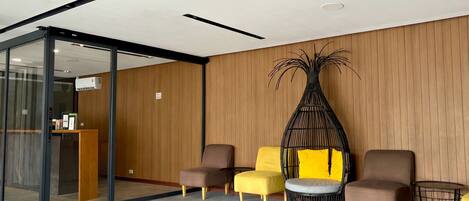 A reception area with a glass partition, a reception desk, and seating with a yellow cushion.