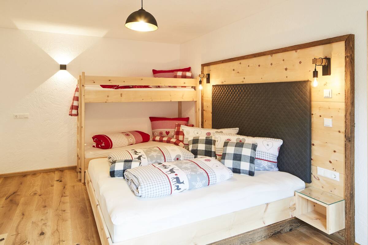 A bunk bed room with a wooden headboard, a bedside table, and a hanging light fixture.
