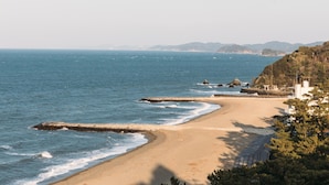 Una spiaggia con un litorale sabbioso, mare calmo e affioramenti rocciosi.