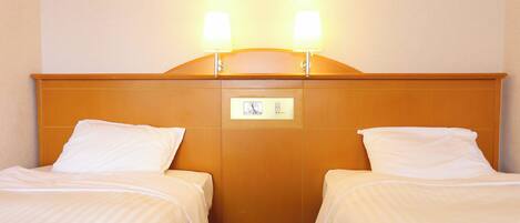A hotel room with two single beds, a wooden headboard, and two bedside lamps.