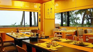 Zona pranzo con tavoli apparecchiati, ampie finestre vista alberi e arredamento in stile tradizionale giapponese.