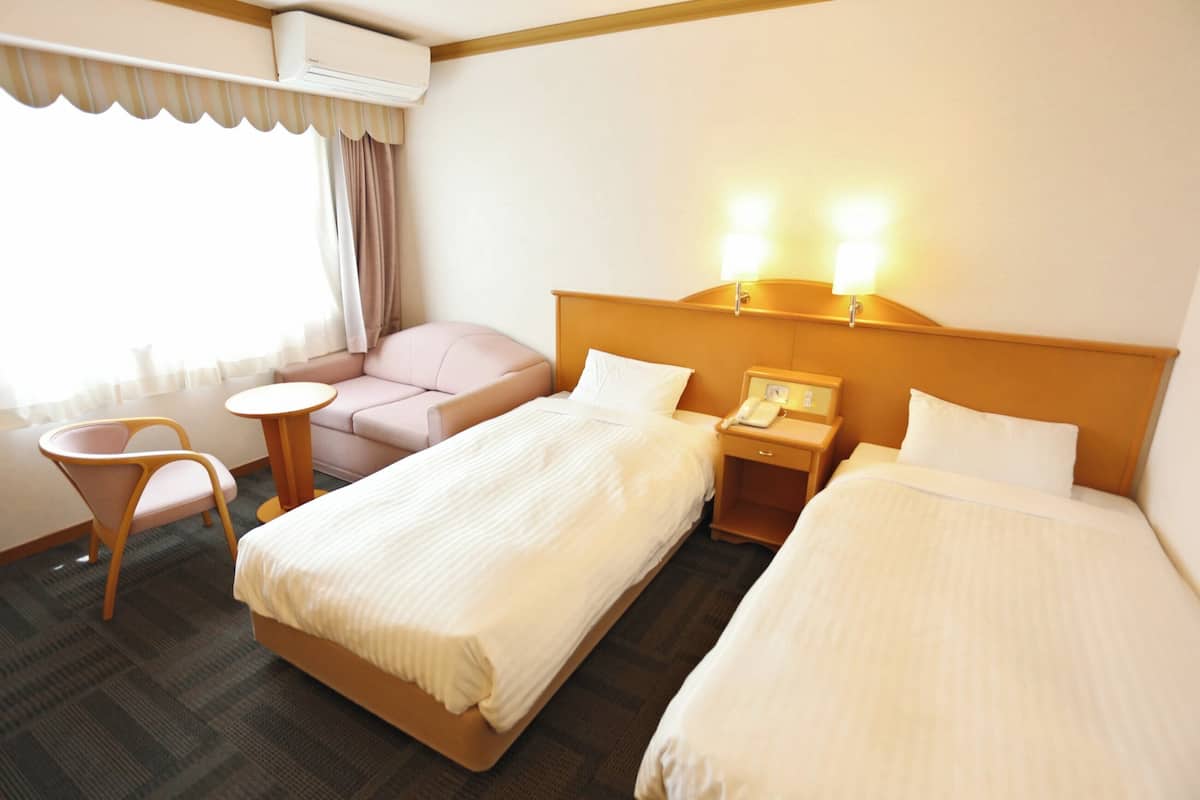 Una habitación de hotel con dos camas, un sofá, una mesita y una silla.