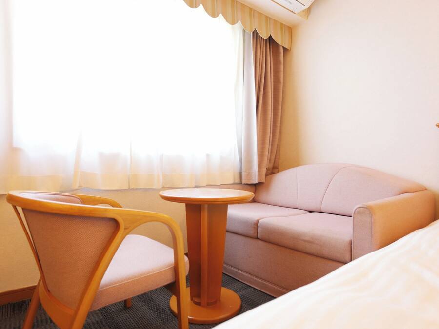 A hotel room with a bed, a sofa, a chair, and a small round table.