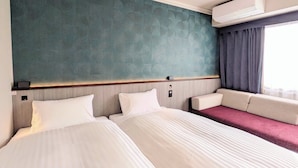 Una camera d'albergo con due letti, una parete verde con texture, un condizionatore d'aria e una finestra con tende.