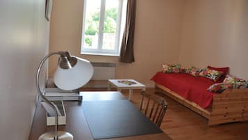 Une chambre à coucher avec un lit en bois, un bureau avec une lampe, une petite table et une fenêtre avec des rideaux.