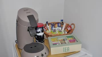 A coffee maker, a basket of tea bags, and a box of Lipton tea on a table.