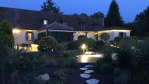 Une maison avec un chemin de jardin menant à l’entrée, entourée de différentes plantes et ornée d’une statue de flamant rose.