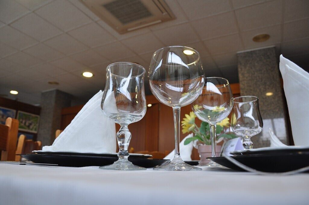 A table set with three wine glasses and a folded napkin, with a vase of flowers in the background.