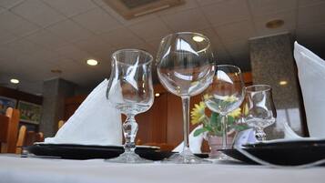 A table set with three wine glasses and a folded napkin, with a vase of flowers in the background.
