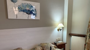 A hotel room with two beds, a painting on the wall, a bedside table with a lamp, and a fruit bowl on the bed. - Boncompte (Ponts)