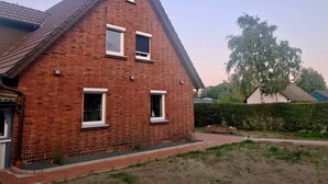 A red brick house with a gabled roof, two windows, and a small porch area. - Ferienwohnungen Möwe (Lembruch)