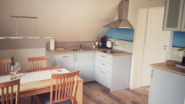 A compact kitchen with a dining table, chairs, and a sink.