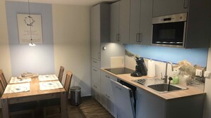 A modern kitchen with grey cabinets, a black microwave, and a coffee maker on the counter. - Ferienwohnungen Möwe (Lembruch)