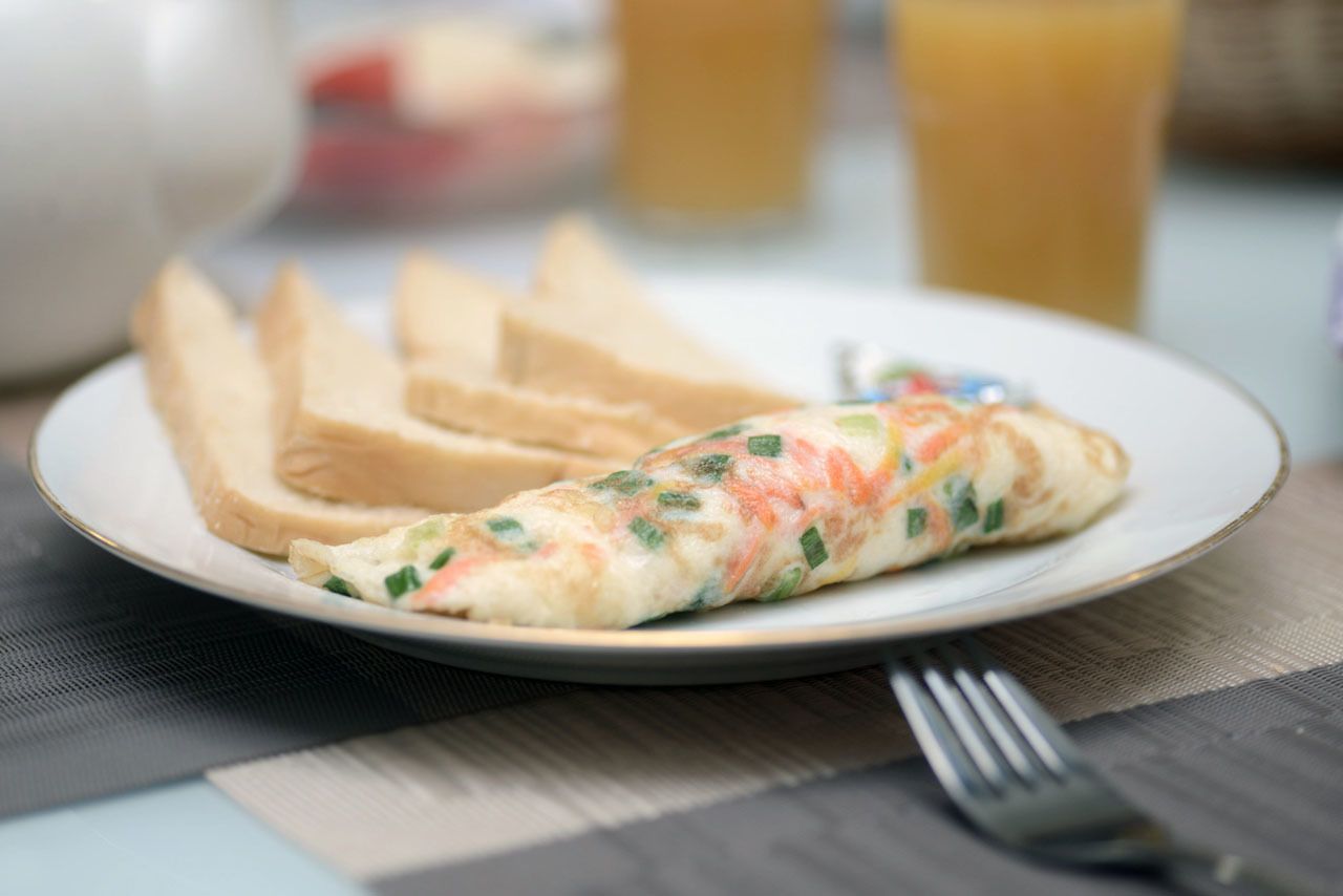 A plate with an omelette and slices of toast on a table.