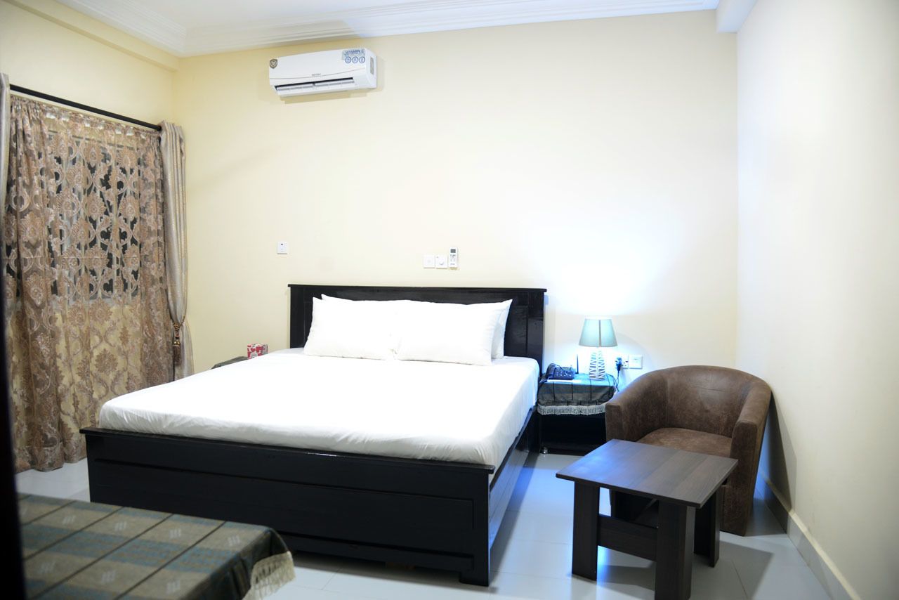 Un dormitorio con cama, mesita de noche, silla y mesa.