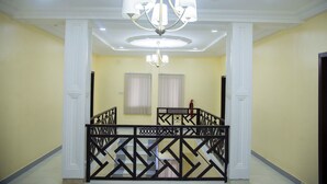 Ein geräumiger Raum mit hoher Decke, einem Kronleuchter, einer Treppe mit dekorativer Geländer und einem Feuerlöscher an der Wand.