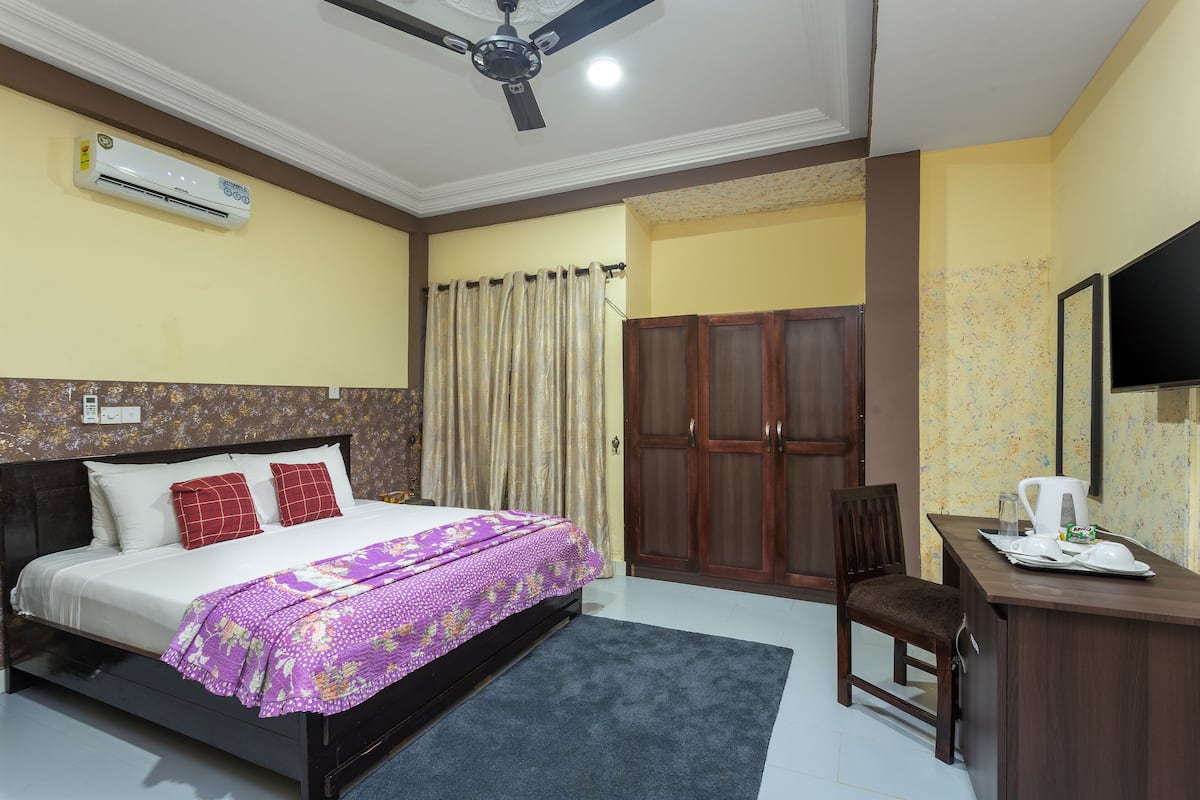 Une chambre à coucher comprenant un lit, un bureau, une chaise, un climatiseur et une armoire.