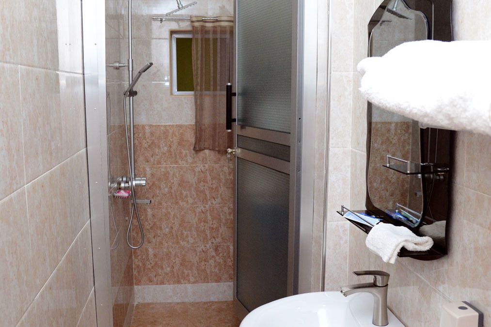 Un baño con ducha, lavamanos y perchero para toallas.