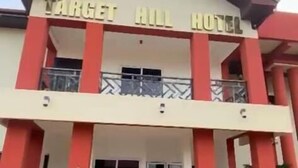 Das Target Hill Hotel mit zwei Etagen, einem zentralen Eingang, Balkonen und Pflanzgefäßen.