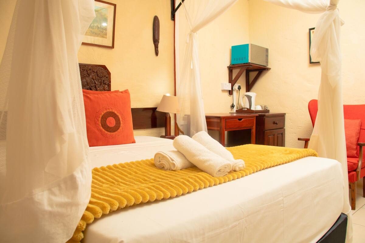 A hotel room with a bed, a desk, a chair, and a bathroom.