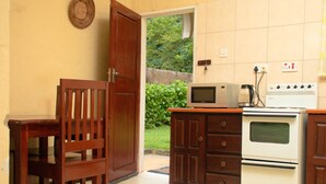 Eine Küche mit Mikrowelle, Backofen, einem Holzstuhl und einer Tür zu einem Garten.