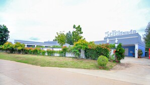 A building with a sign reading "Sujisannon" surrounded by greenery and a paved area. - OYO 330 Venus Resort Pranburi (Pranburi)
