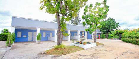 A building with a blue facade, white columns, and a central courtyard with a fountain and potted plants.