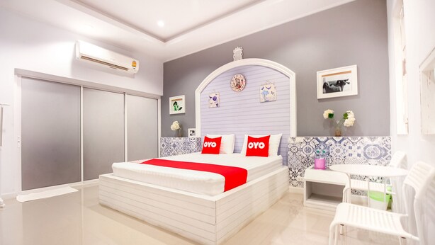 A modern bedroom with a large bed, a bedside table, a chair, and a wardrobe. - OYO 330 Venus Resort Pranburi (Pranburi)