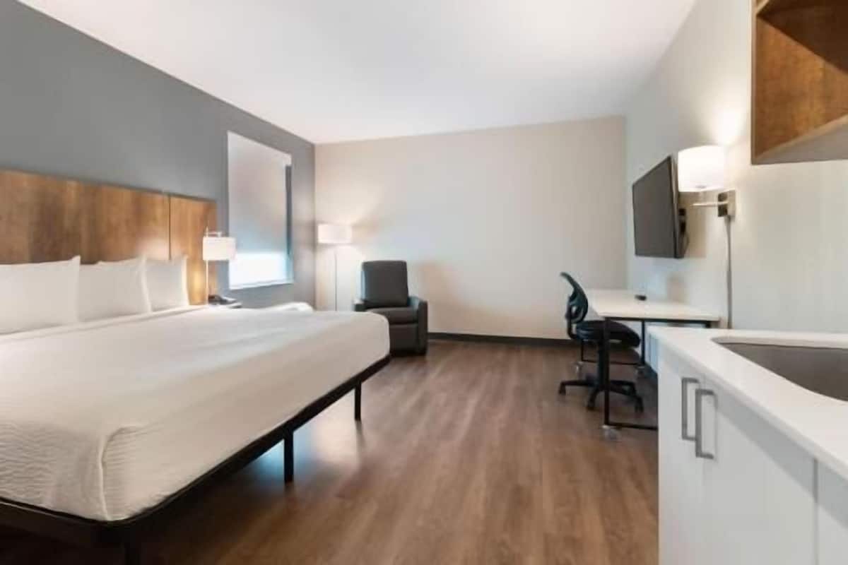 Ein Hotelzimmer mit Bett, Schreibtisch, Stuhl und Fernseher.