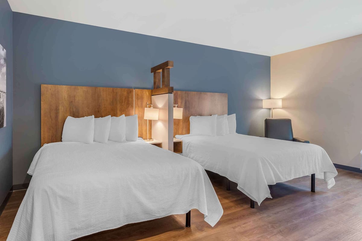 Ein Hotelzimmer mit zwei Betten, Holz-Kopfteilen und Nachttischlampen.