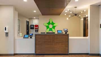 A reception desk with a modern design, a digital display, and a unique green logo.