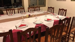 A dining area with a long table set for a meal, surrounded by wooden chairs. - Casa Polín (Vega de Valcarce)