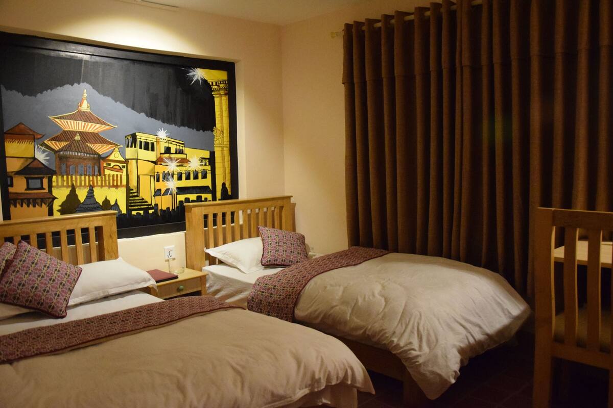 A hotel room with two beds, a nightstand, a lamp, a painting of a traditional building, and a curtain.