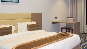 A hotel room with a bed, a desk, and a chair.