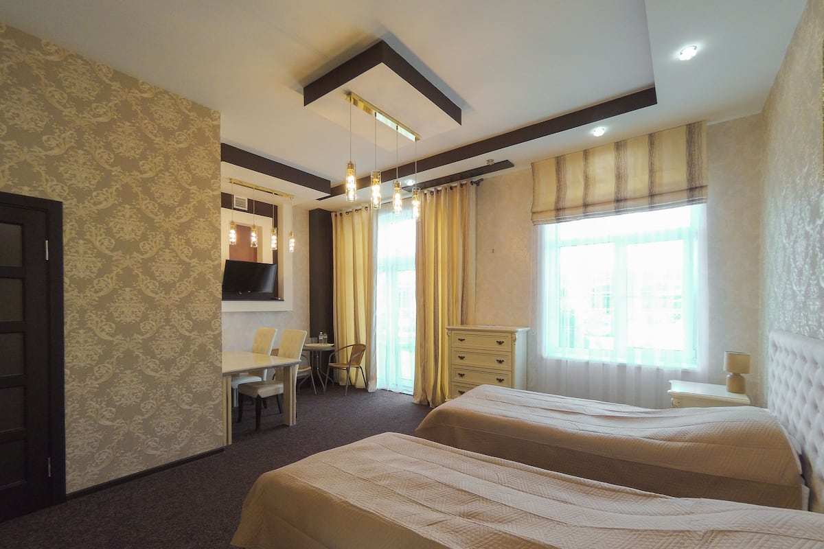 Una habitación de hotel con dos camas, un escritorio con silla, televisión y ventana con cortinas.