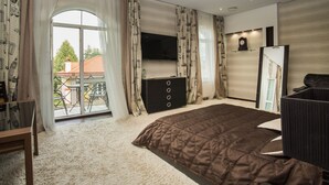 Un dormitorio con una cama grande, un televisor montado en la pared, un aparador y un balcón con vistas al exterior.