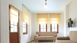 Amplia sala de estar con un sofá color beige, una puerta de madera y un televisor de pantalla plana montado en la pared.