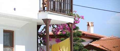 Un edificio de dos pisos con balcón, piscina y mobiliario exterior.