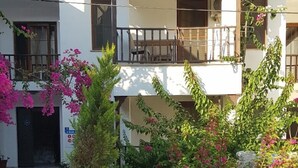 Un edificio con balcón, plantas en macetas y cielo despejado.