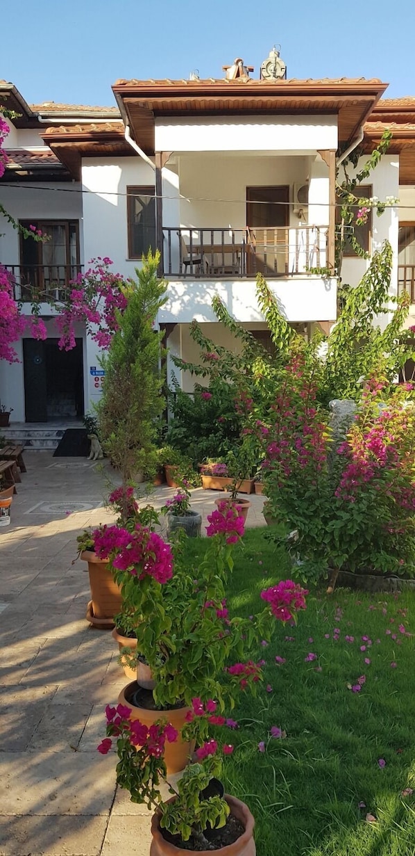 Un edificio con balcón, plantas en macetas y cielo despejado.
