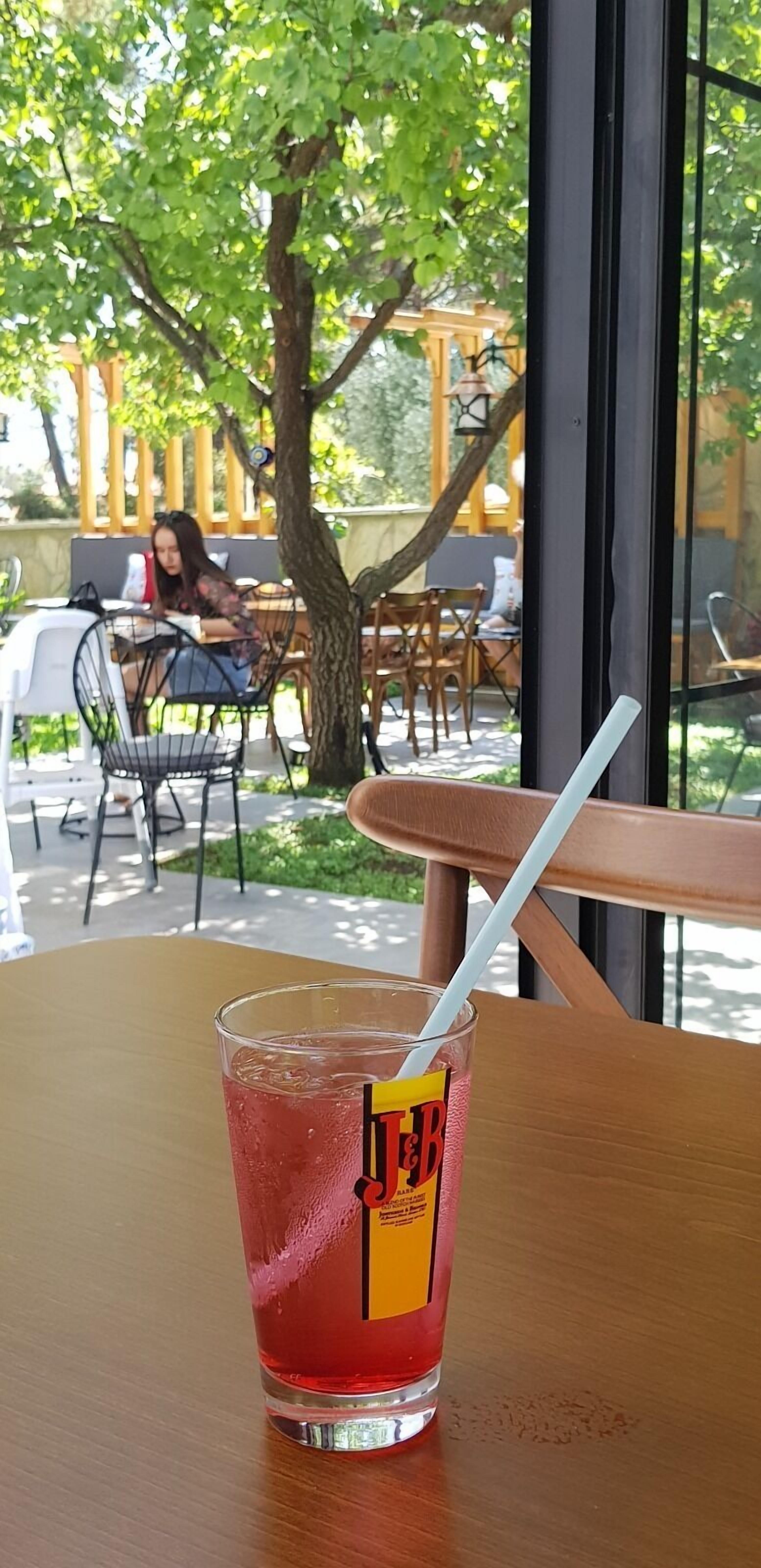 A glass of iced beverage with a straw on a wooden table.